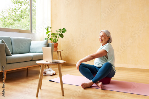 Mature woman doing Seated twist near laptop