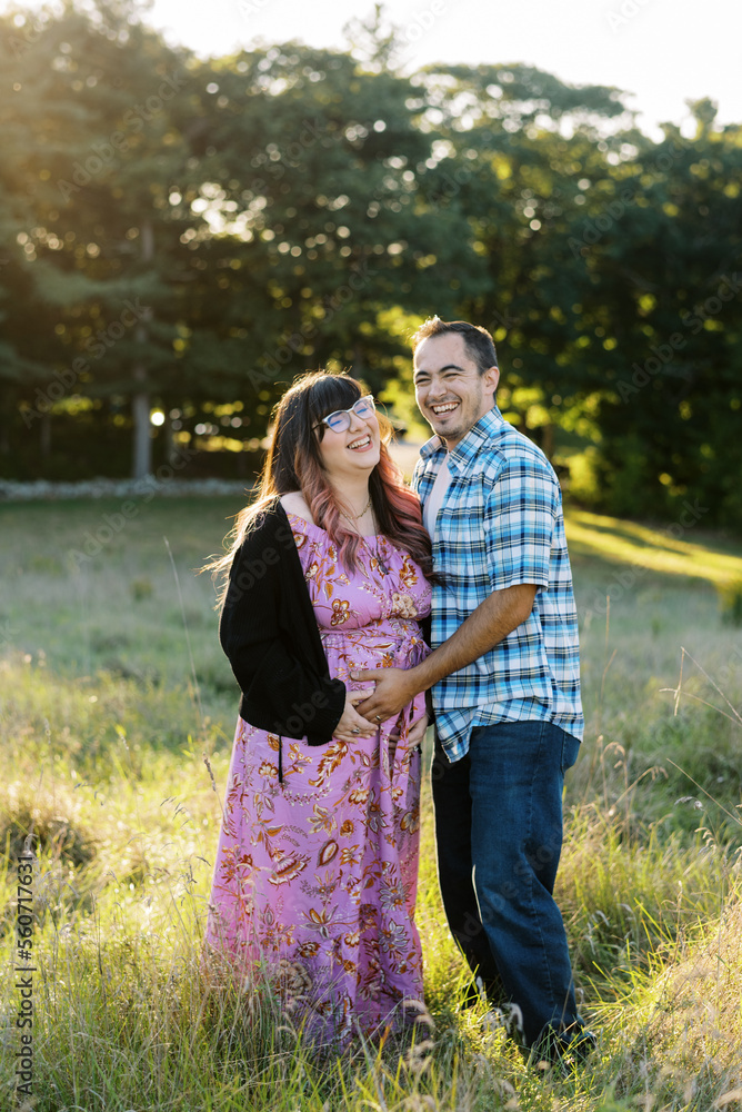 Expectant Couple hugging each other in a field. Expectant Couple hugging each other in a field.