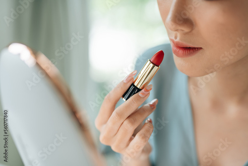 A beautiful elegant woman applying lipstick using a mirror photo