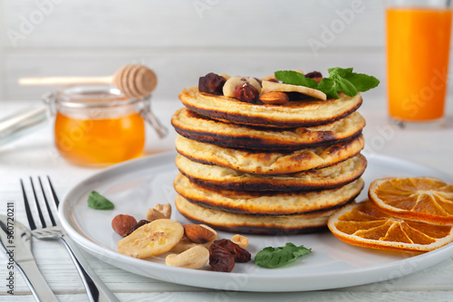 Fresh  delicious pancakes with dried bananas  oranges  nuts and honey on a plate.
