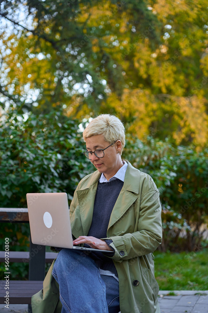 an adult busy woman is sitting in the park with a laptop
an adult busy woman is sitting in the park with a laptop