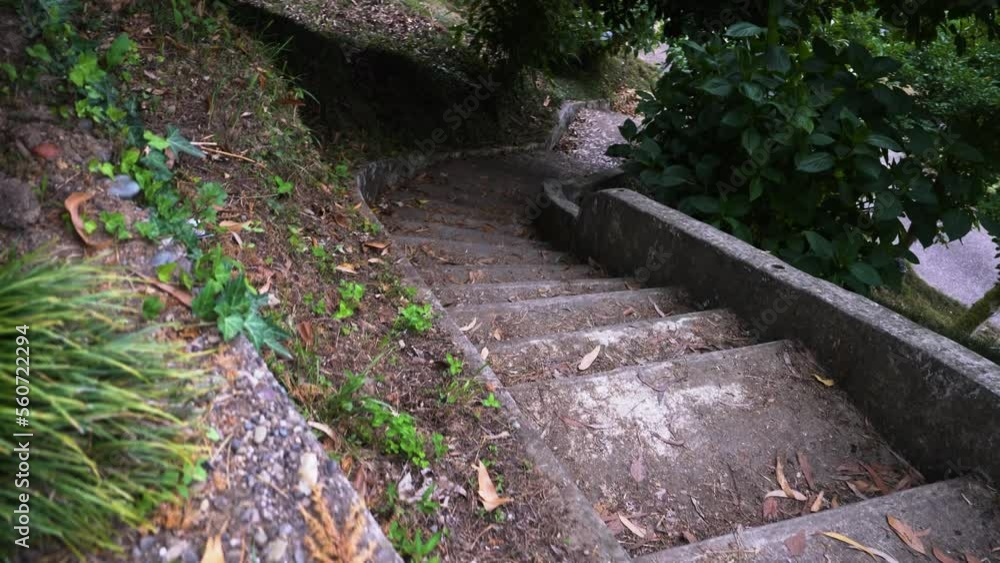 A concrete staircase leading down the outer corner of a gray concrete building leads to a road. A concrete staircase leading down the outer corner of a gray concrete building leads to a road.