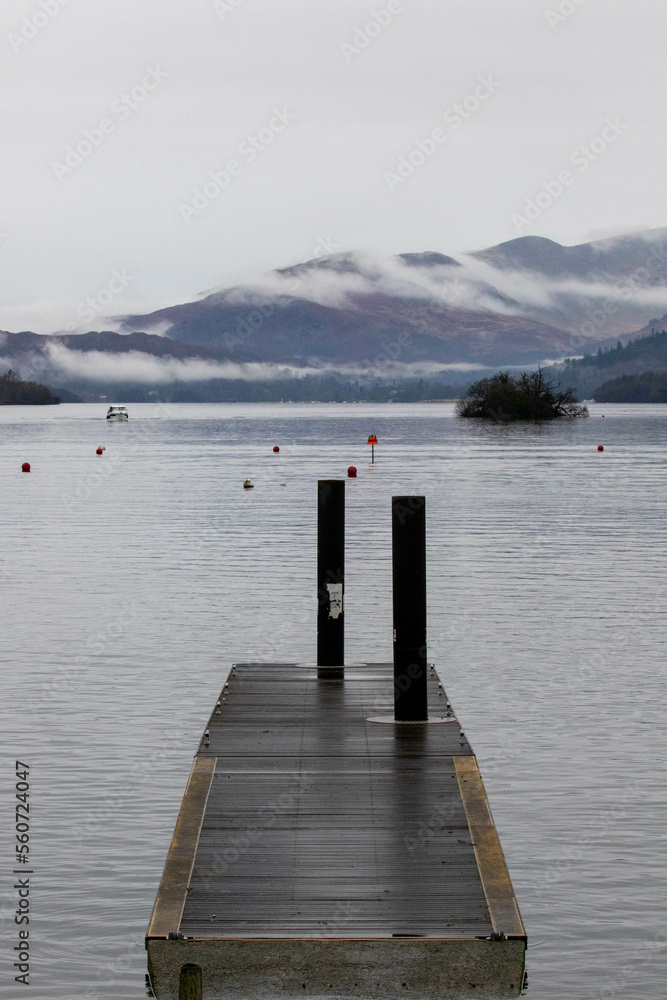 Naklejka premium Jetty on lake Windermere with fog rolling over the mountains
