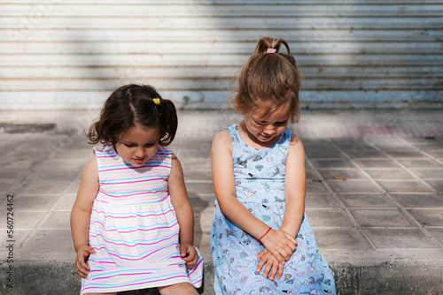 Charming little girls sitting on pavement photo