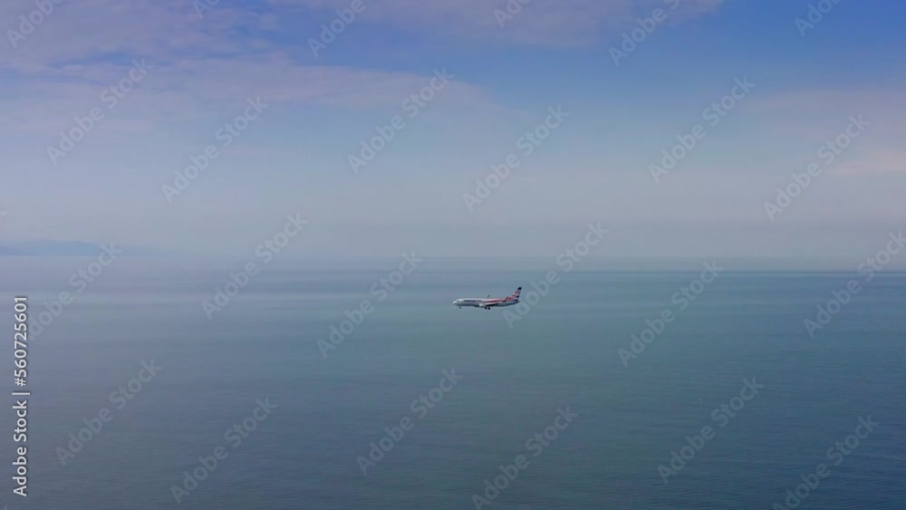 Passenger airplane flying over Black sea expanse and touching down at the airport among Batumi morning cityscape Passenger airplane flying over Black sea expanse and touching down at the airport among Batumi morning cityscape