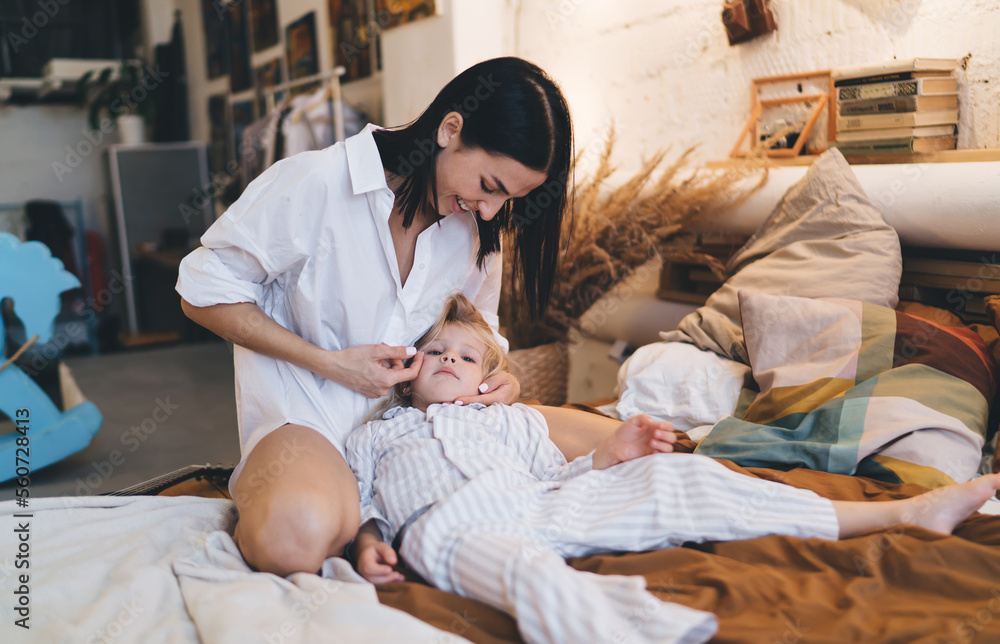 Joyful mother caressing daughter in bed