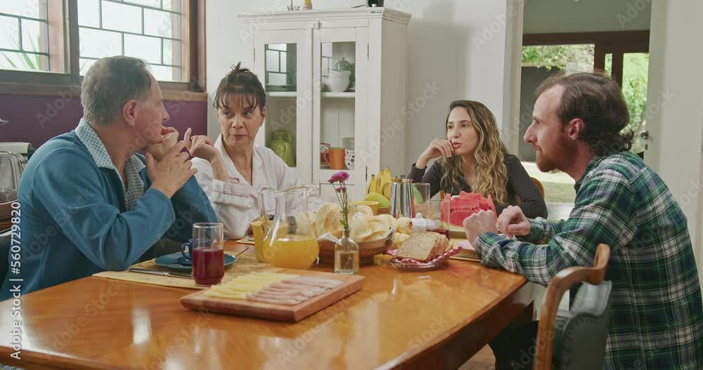 Family eating breakfast together. Mature couple with young adults son and daughter seated at morning table. Older parents and grown adults Family eating breakfast together. Mature couple with young adults son and daughter seated at morning table. Older parents and grown adults