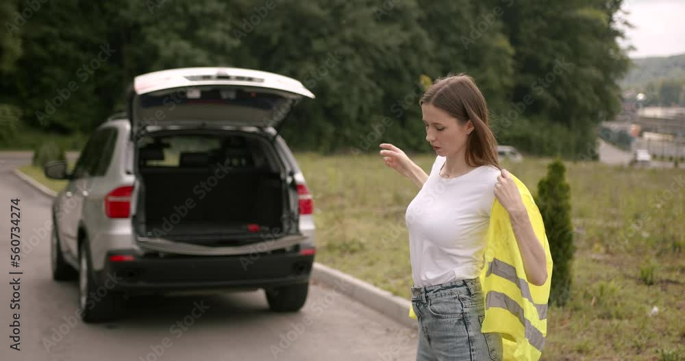 LYoung woman in vest calling for roadside service LYoung woman in vest calling for roadside service