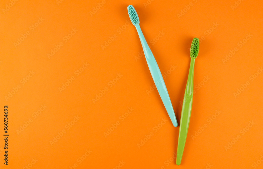 Blue and green toothbrushes on orange background Blue and green toothbrushes on orange background