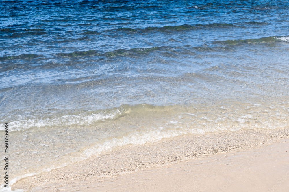 Ocean wave on tropical beach with golden sand and ripple of water splash from emerald blue-green sea water during summer vacation. 