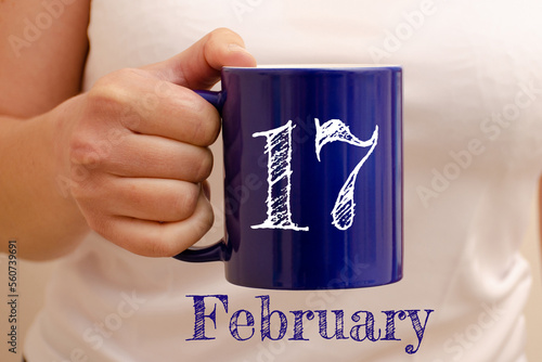 The inscription on the blue cup 17 february. Cup in female hand, business concept
