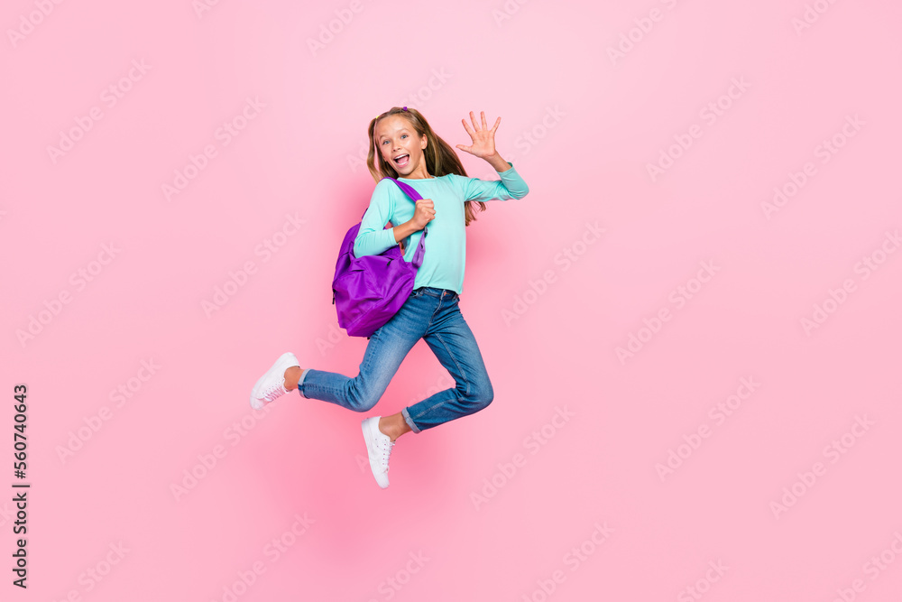 Full length portrait of active energetic schoolkid jumping raise arm isolated on pink color background