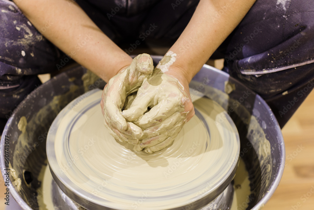 Pottery workshop. Closeup of woman artist hands molding clay on pottery wheel. Creative handmade craft. Ceramic art studio.