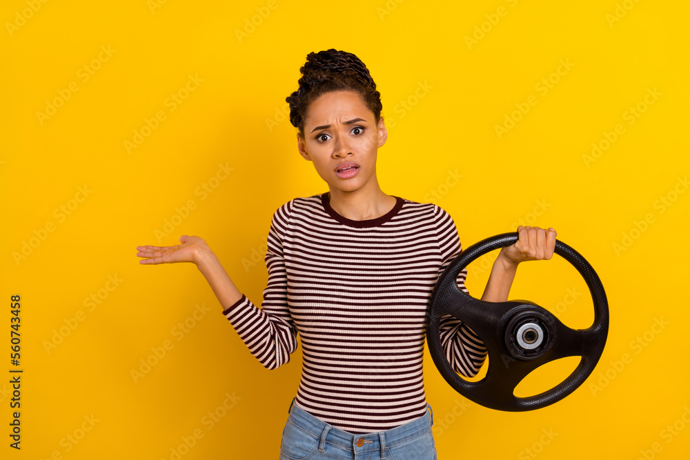 Portrait of clueless young person shrug shoulder hand hold wheel isolated on yellow color background Portrait of clueless young person shrug shoulder hand hold wheel isolated on yellow color background