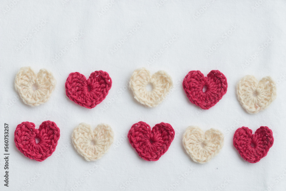 Crocheted amigurumi pink and white hearts on a white background. Valentine's banner top view Crocheted amigurumi pink and white hearts on a white background. Valentine's banner top view