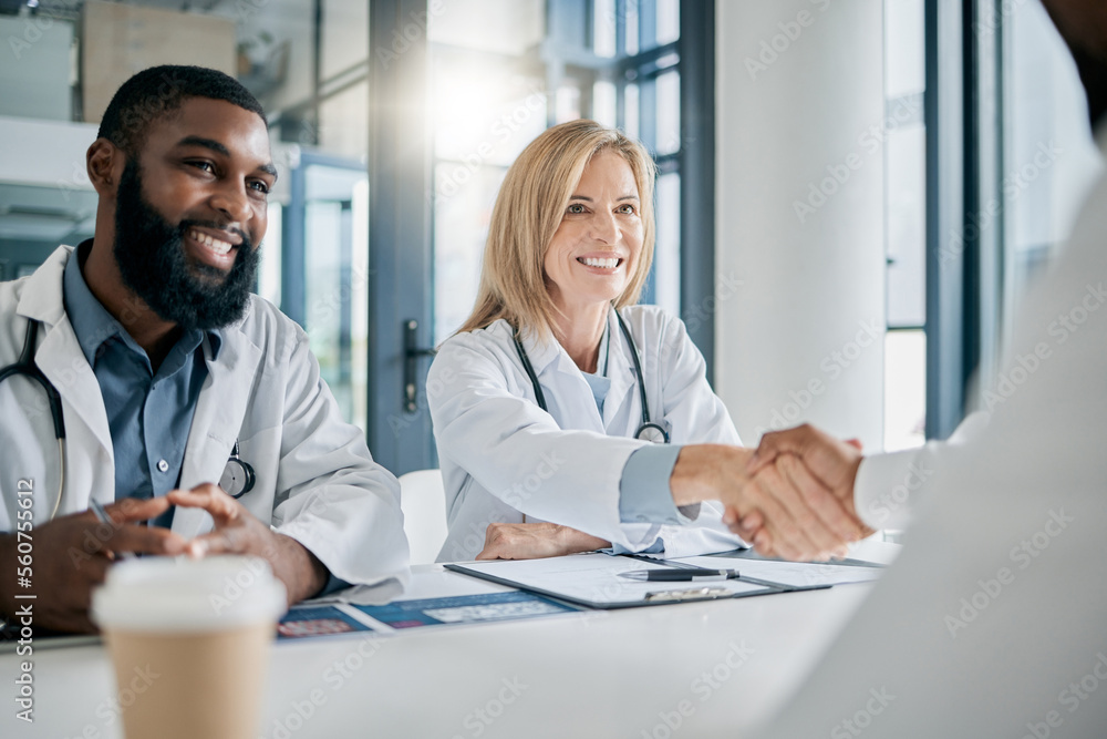 Obraz premium Handshake, partnership or happy doctors in a meeting after successful medical surgery or reaching healthcare goals. Teamwork, woman or black man smiles shaking hands with a worker in hospital office