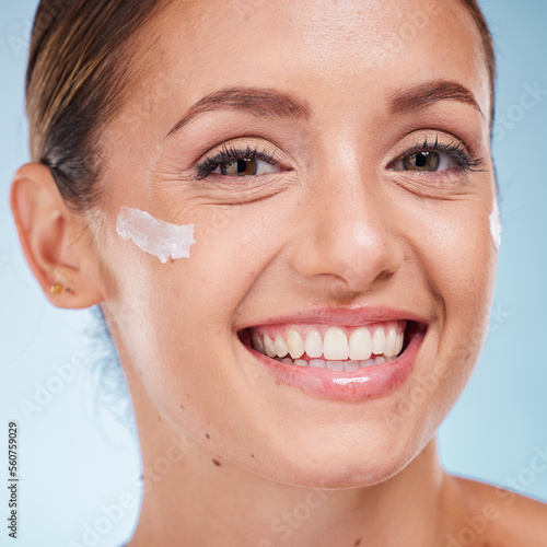 Skincare, beauty and portrait of a woman with face cream for health, wellness and natural face routine. Cosmetic, happy and model with facial lotion, spf or creme isolated by a blue studio background