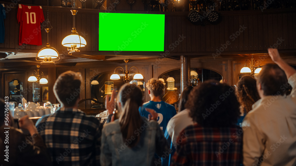 Group of Multicultural Friends Watching a Live Sports Match on TV with Green Screen Display in a Bar. Happy Fans Cheering and Shouting, Celebrating When Team Scores a Goal and Wins the Tournament. - obrazy, fototapety, plakaty 
