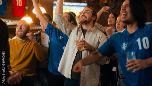 Group of Soccer Fans Watching a Live Football Match Broadcast in a Sports Pub on TV. People Cheering, Supporting Their Team. Crowd Goes Ecstatic When Team Scores a Goal and Wins the Championship.