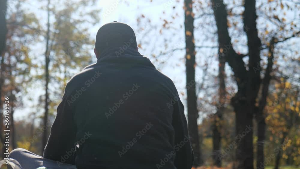 back view. a man in a cap and with a beard sits in an autumn park back view. a man in a cap and with a beard sits in an autumn park