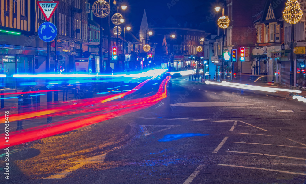 Neon bright Night trail of cars and ambulance in town road England