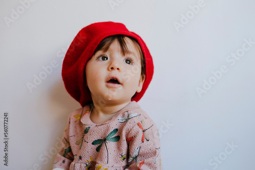 Cute baby girl drooling while looking up against wall at home photo
