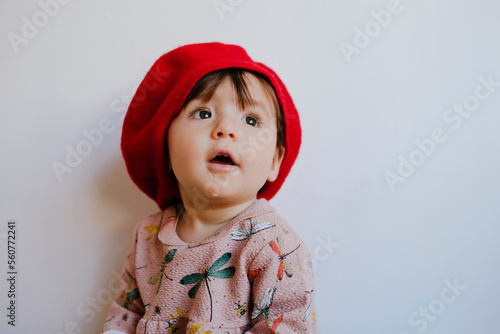 Cute baby girl drooling while looking up against wall at home