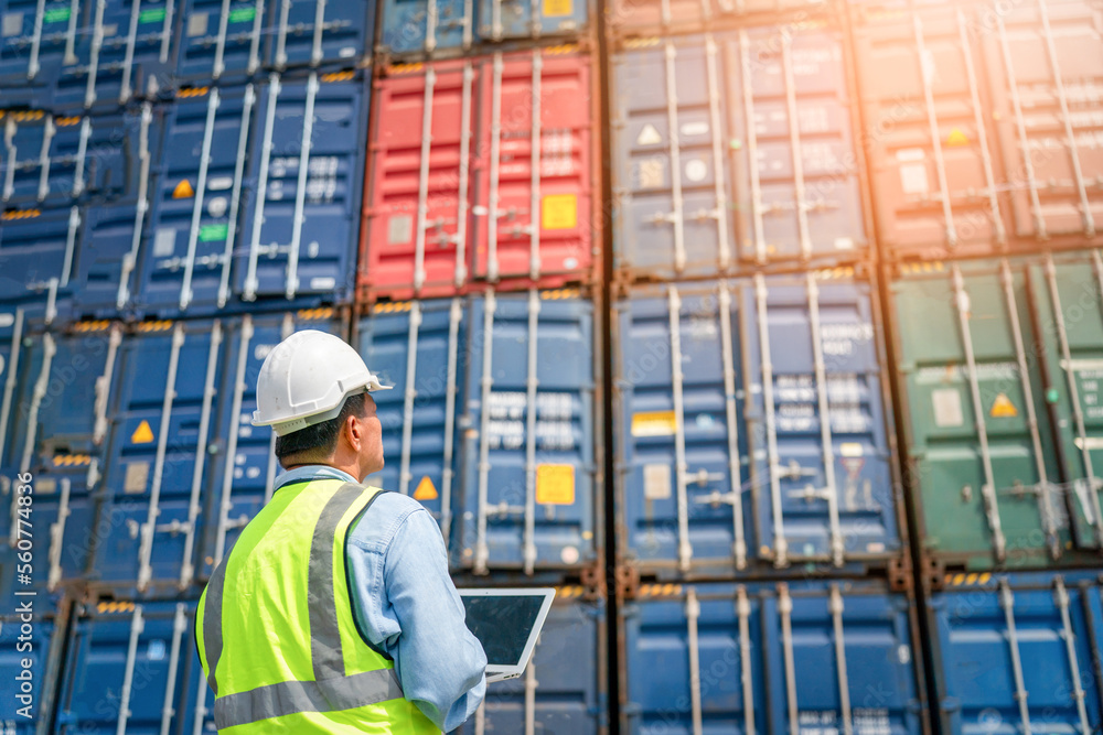 Engineer wears PPE checking container storage with cargo container background at sunset. Logistics global import or export shipping industrial concept. Engineer wears PPE checking container storage with cargo container background at sunset. Logistics global import or export shipping industrial concept.