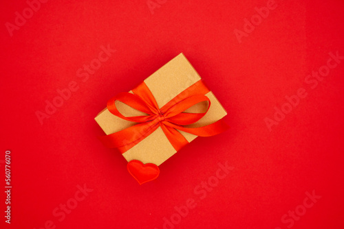 Wrapped brown present box with red ribbon bow, isolated on red. The concept of the holidays