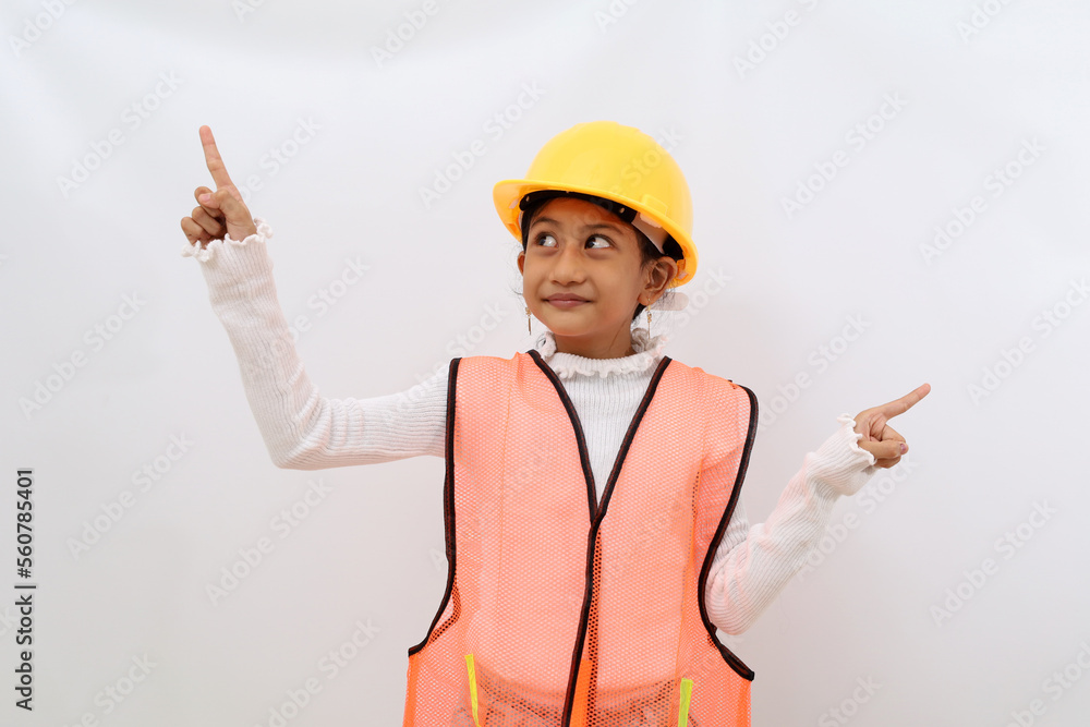 Happy Asian little girl in the construction helmet as an engineer standing while pointing left and right side. Isolated on white with copyspace Happy Asian little girl in the construction helmet as an engineer standing while pointing left and right side. Isolated on white with copyspace