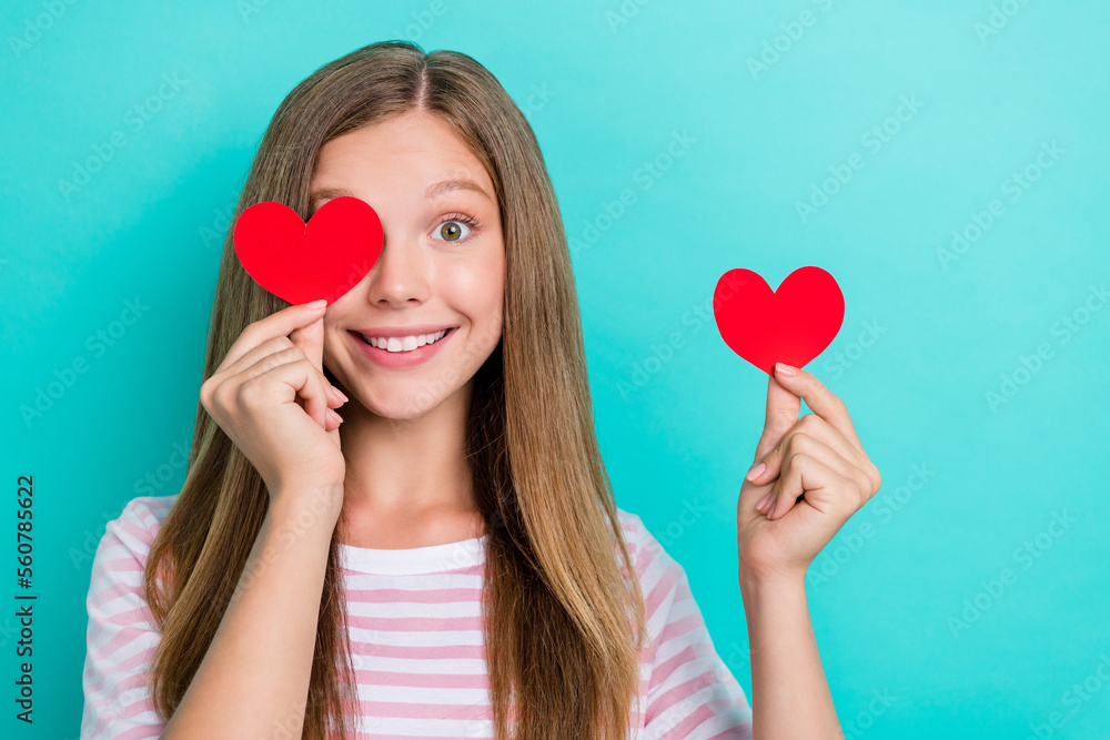 Photo of tricky charming girl dressed pink t-shirt smiling holding heart cover eye empty space isolated teal color background Photo of tricky charming girl dressed pink t-shirt smiling holding heart cover eye empty space isolated teal color background