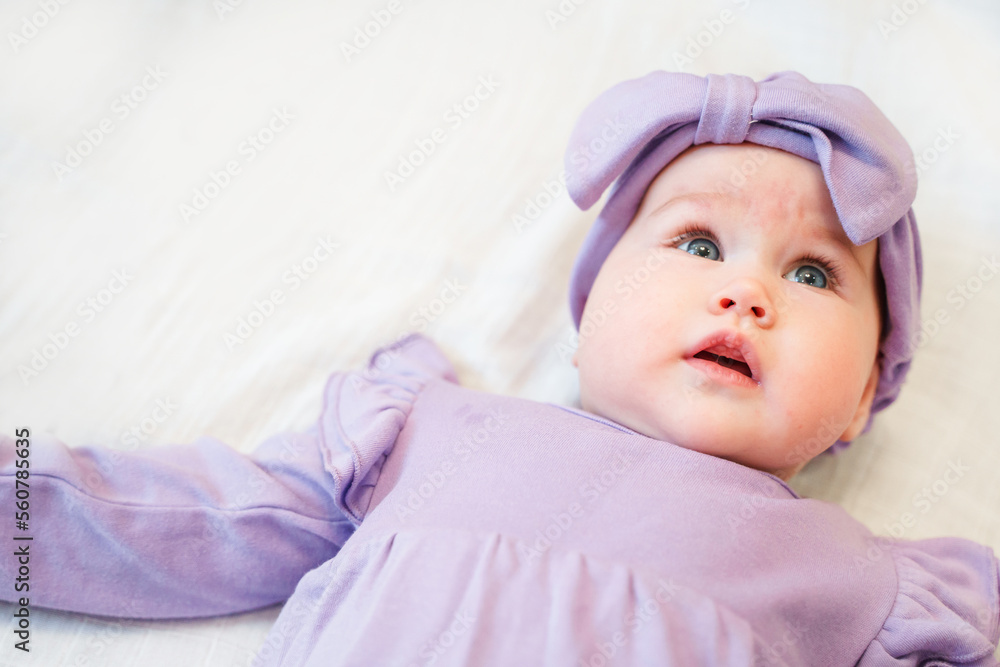 Portrait of a charming little girl toddler in a dress lying on a white sheet Portrait of a charming little girl toddler in a dress lying on a white sheet