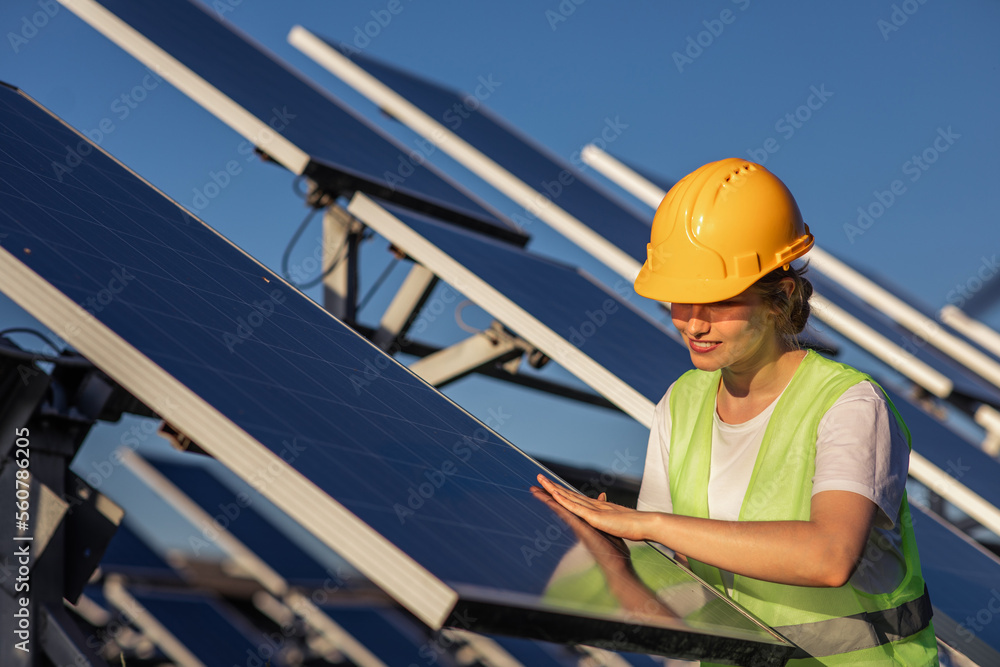 Smiling happy lady at photovoltaic solar farm she carefully check the cleanliness of the photovoltaic solar panels she wearing safety equipment Smiling happy lady at photovoltaic solar farm she carefully check the cleanliness of the photovoltaic solar panels she wearing safety equipment