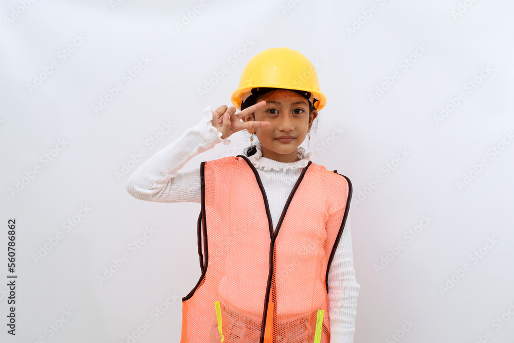 Cute Asian little girl in the construction helmet as an engineer posing confidently looking at the camera. Isolated on white