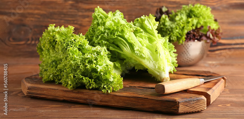 Cutting board with fresh lettuce and knife on wooden background photo