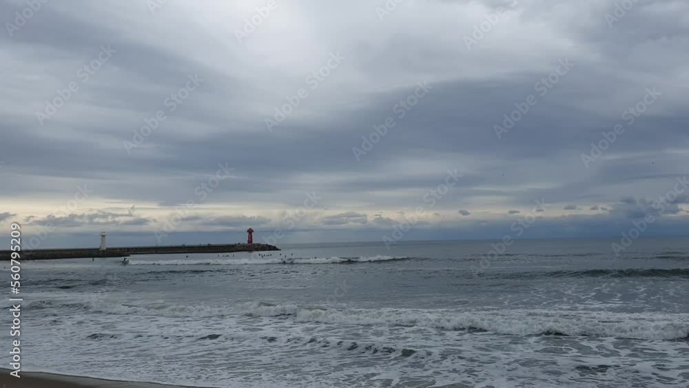 Wavy winter sea, surfers and lighthouse Wavy winter sea, surfers and lighthouse