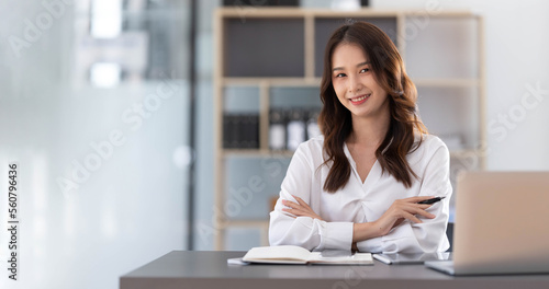 Charming Asian woman working at the office using a laptop Looking at the camera.