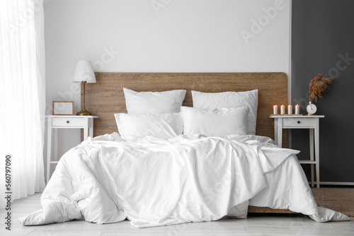Interior of light bedroom with bedside tables and big bed