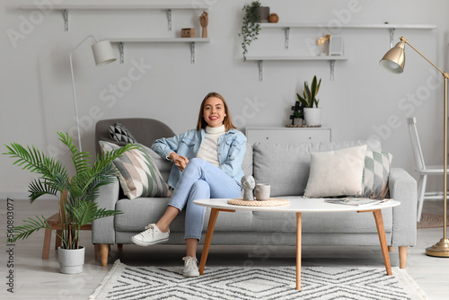 Young woman sitting on grey...