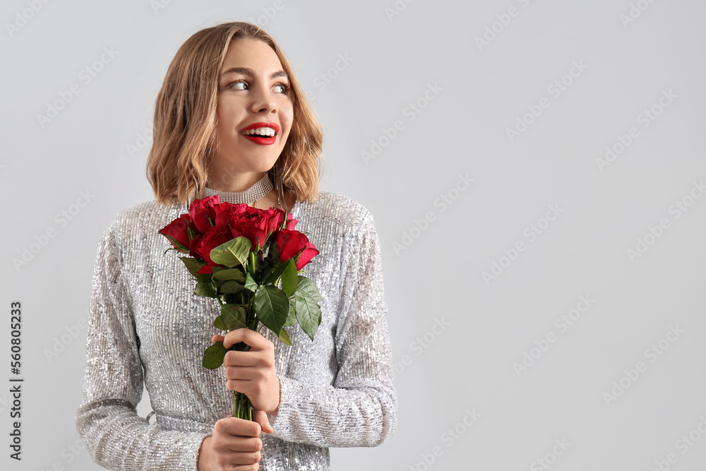 Beautiful young woman with bouquet of red roses on light background Beautiful young woman with bouquet of red roses on light background