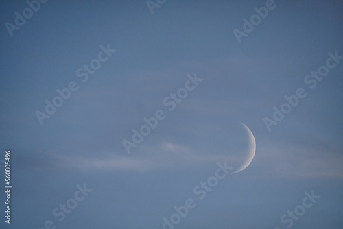 Subtle crescent moon and cloud in blue evening sky