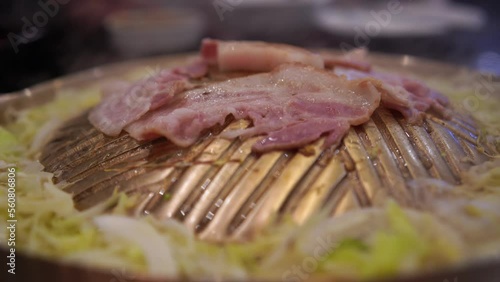Close-up shot of bacons being grilled on a mongolian-japanese style brass pan