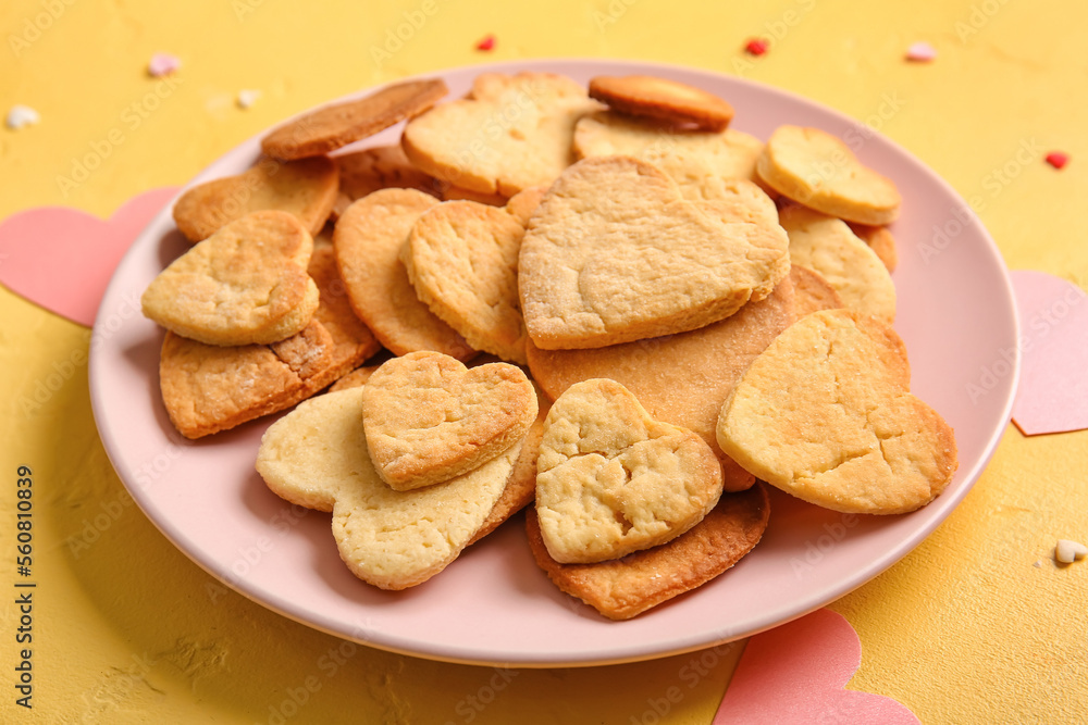 Plate with tasty heart shaped cookies on yellow background, closeup. Valentines Day celebration Plate with tasty heart shaped cookies on yellow background, closeup. Valentines Day celebration