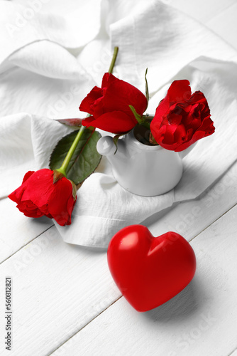 Fototapeta Naklejka Na Ścianę i Meble -  Beautiful rose flowers and heart on light wooden background. Valentines Day celebration