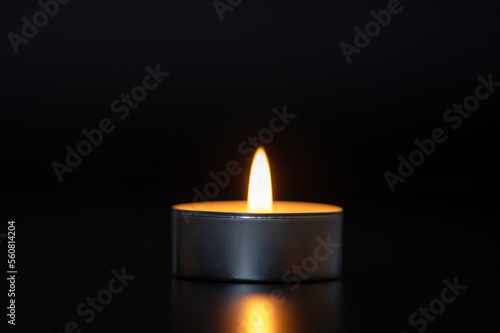One lit candle on a black background