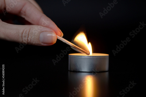 Close up of woman hand lighting candles in the dark night at home