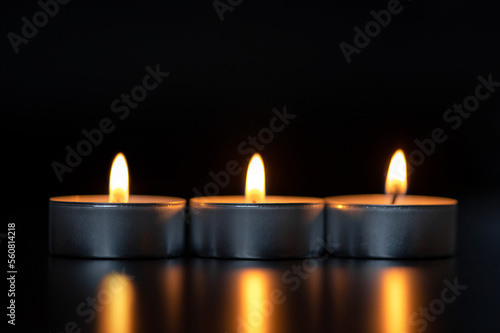 Three burning candles on a black background