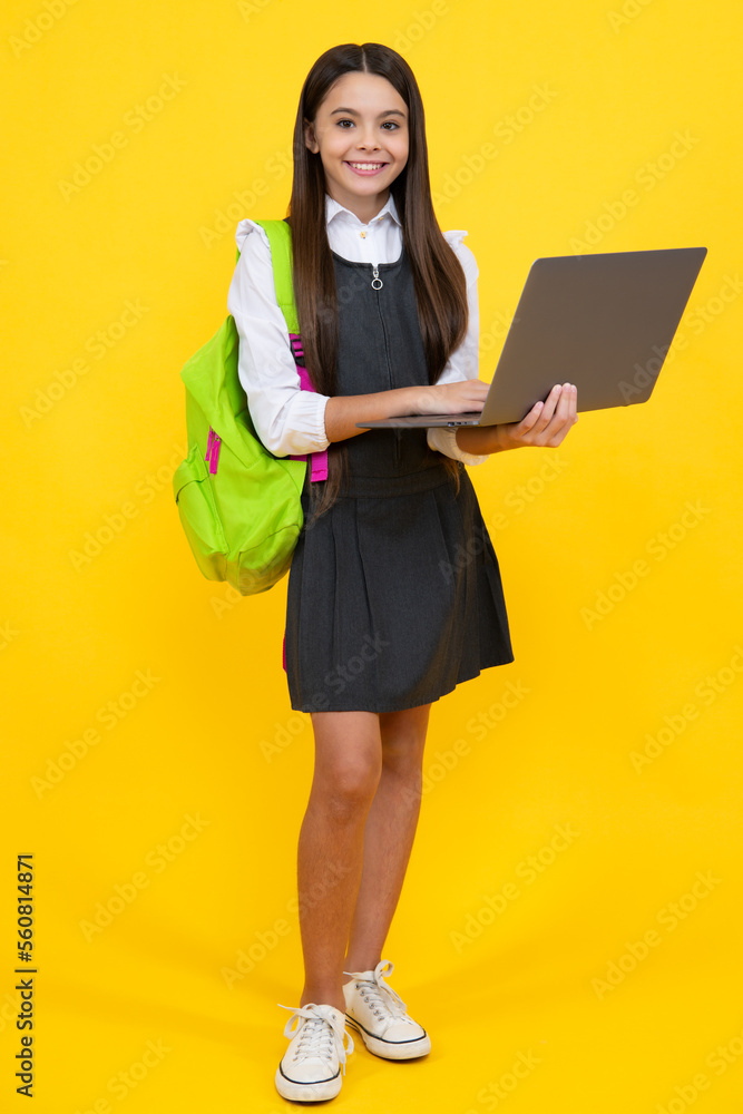 Back to school. Teenager schoolgirl hold notebook laptop. School children on isolated yellow studio background. Happy girl face, positive and smiling emotions. Back to school. Teenager schoolgirl hold notebook laptop. School children on isolated yellow studio background. Happy girl face, positive and smiling emotions.
