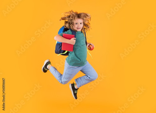 Full length body of little school kid jumping having fun isolated yellow color background. Crazy school boy jump.