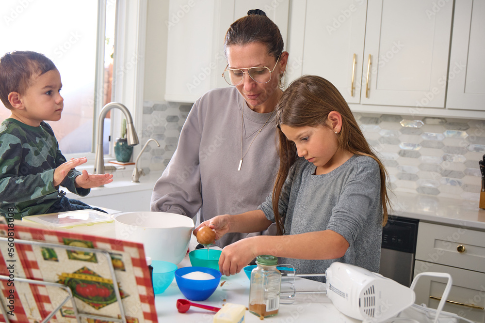 Obraz premium A mother is baking in the kitchen with her young son and daughter